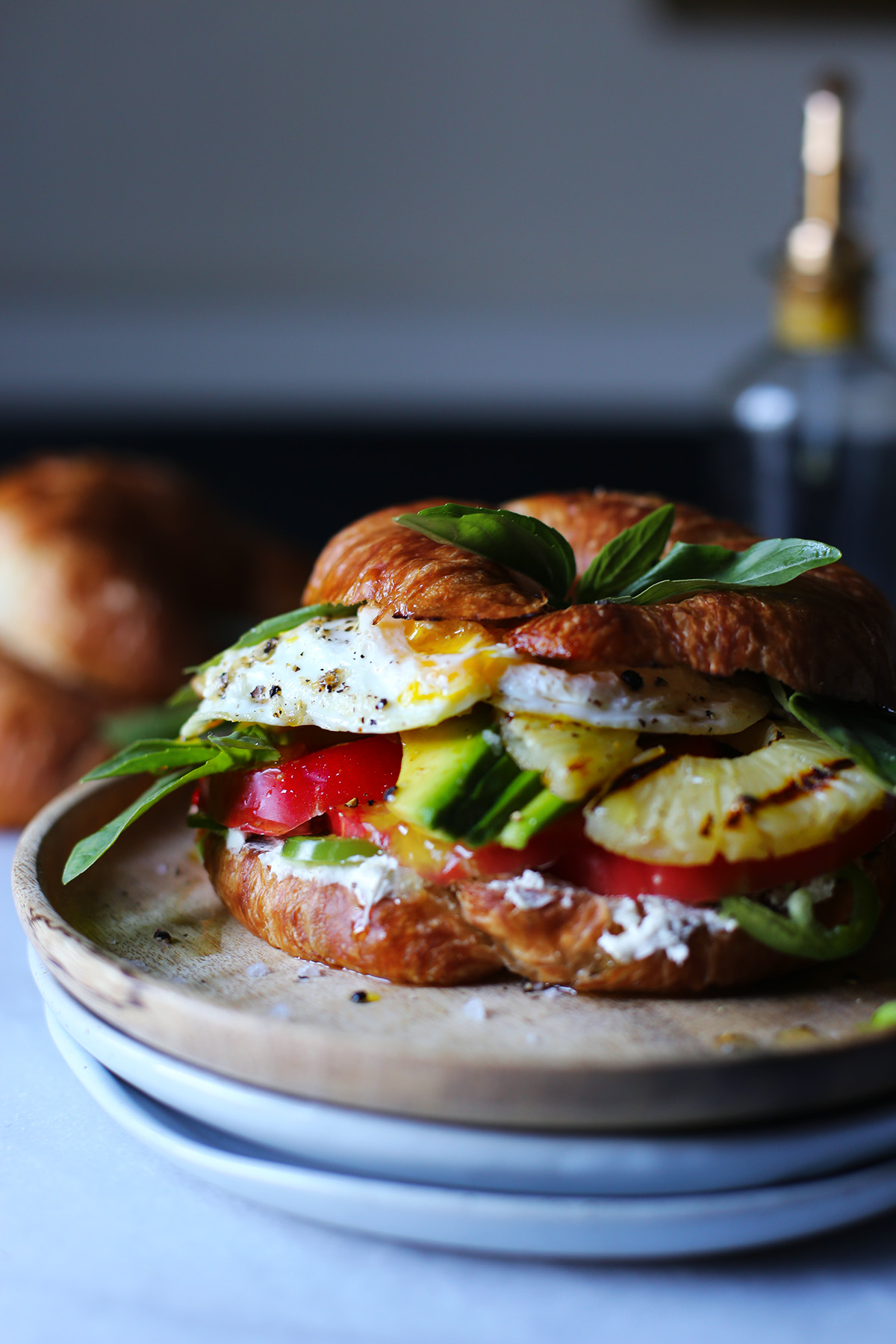Croissant and fried egg sandwich with avocado and grilled pineapple