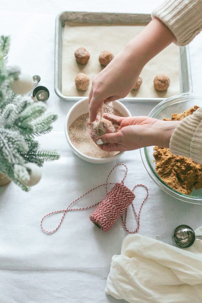 hands dipping cookie dough into chai sugar