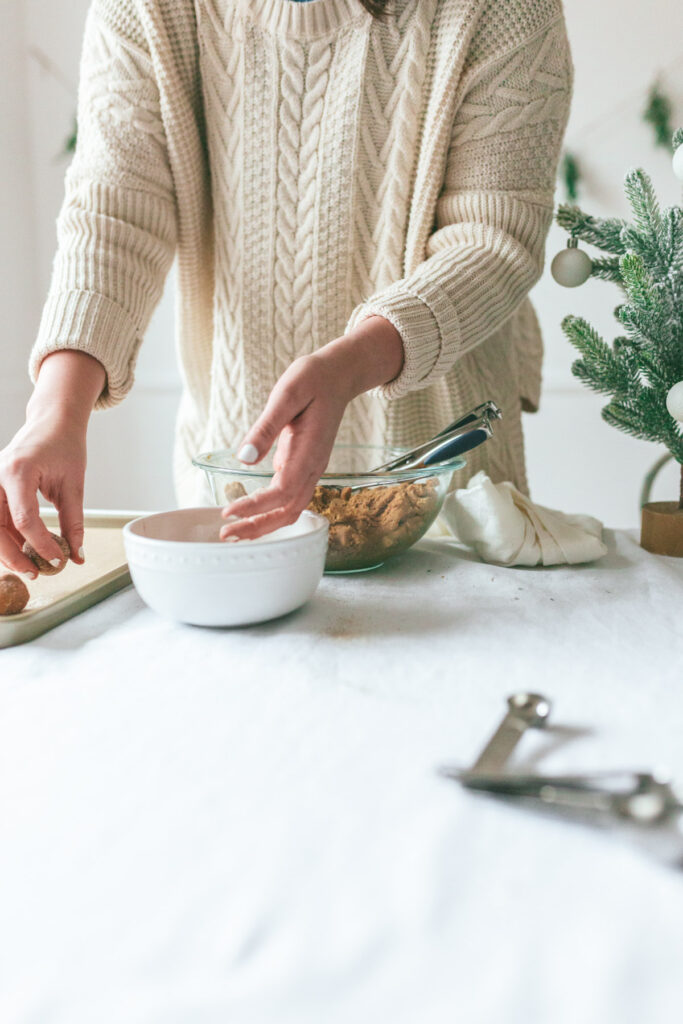 hands dipping cookie dough into chai sugar