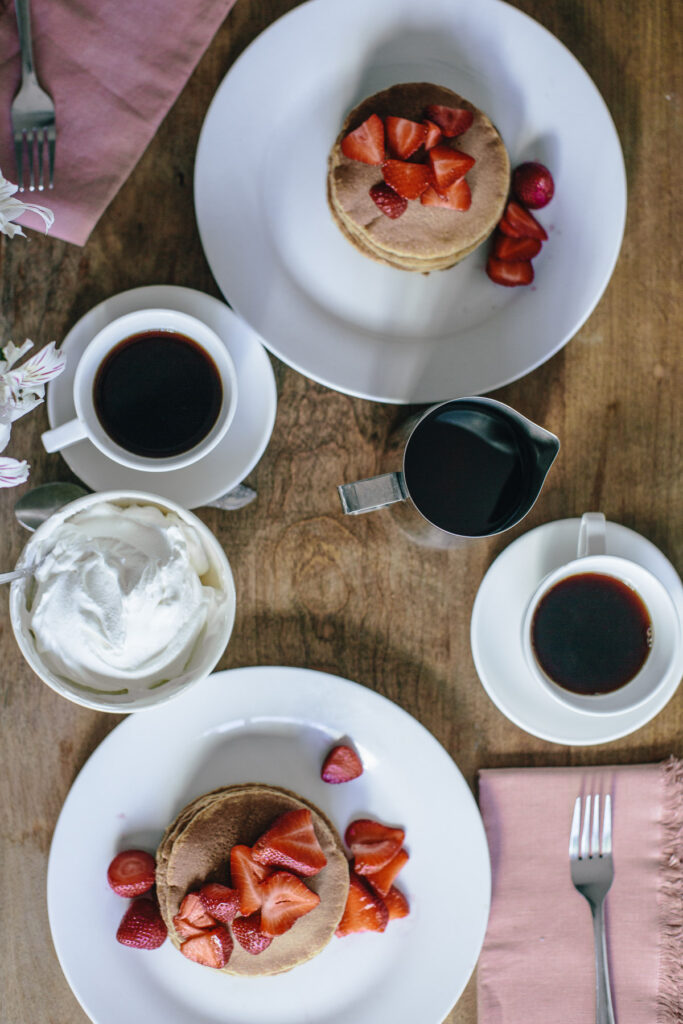 Overhead image of pancakes with strawberries and coffee on the side