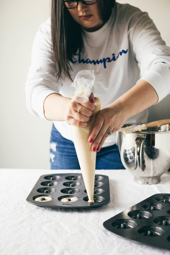 Head on shot of Karlee filling a mini donut pan with the Baked Buttermilk Frosted Mini Donuts batter. 