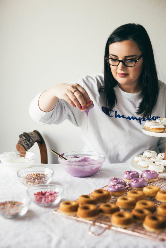 Karlee dipping the Baked Buttermilk Frosted Mini Donuts into purple frosting.