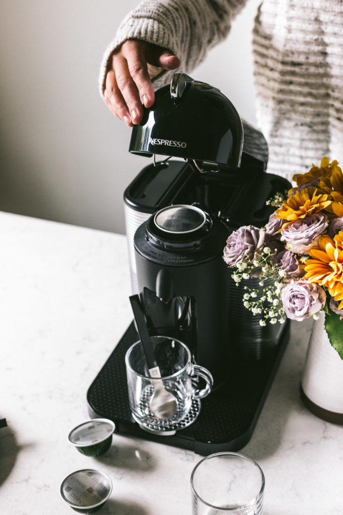 head on image of nespresso machine and a woman behind closing the lid.