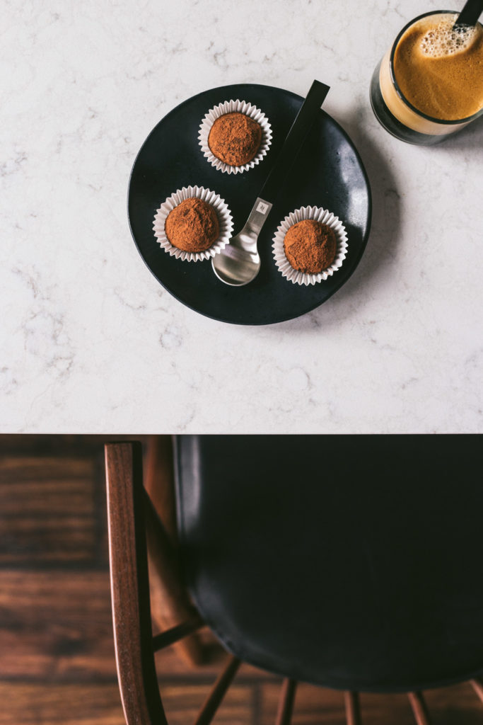 Overhead image of a table and chairs with a small black plate holding 3 truffles