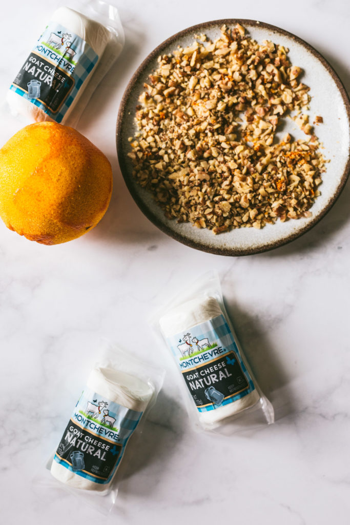 Overhead image on a marble surface. Toasted walnuts on a plate and goat cheese in packaging.