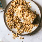 Overhead image on a marble surface. Toasted walnuts on a plate and opened goat cheese bing coated in toasted walnuts