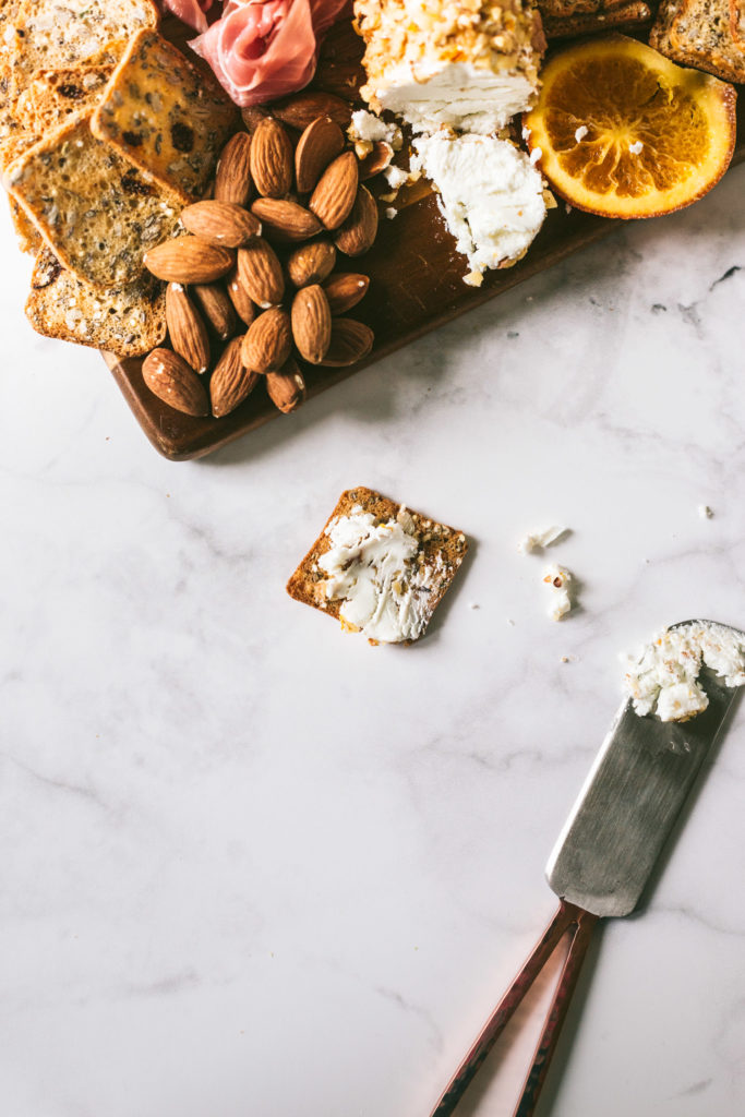 Overhead image on marbled surface of a cracker with the goat cheese spread on the top