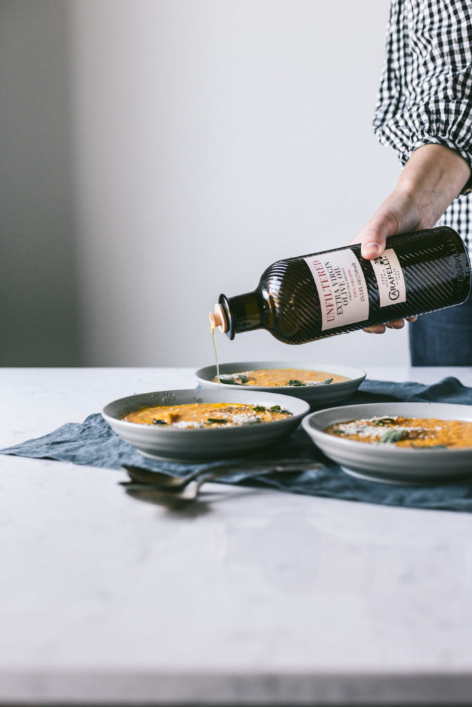 A head on image of olive oil being poured into a bowl of butternut squash soup