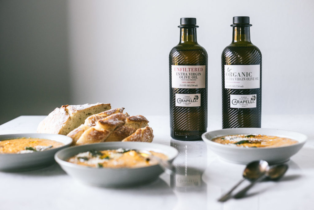 Angled image of butternut squash soup next to a loaf of french bread and olive oil