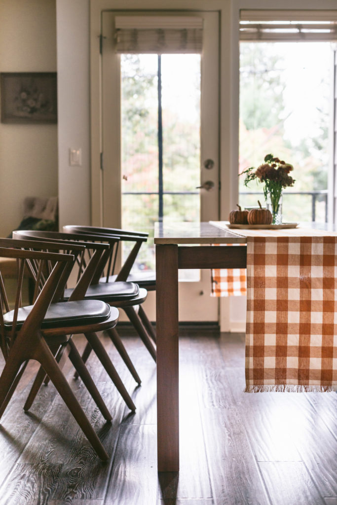 Room & Board dining set with a mustard yellow checkered runner through the middle.