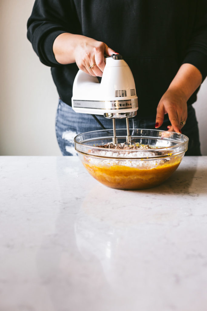 Head on image of karlee using a hand mixer to combine ingredients