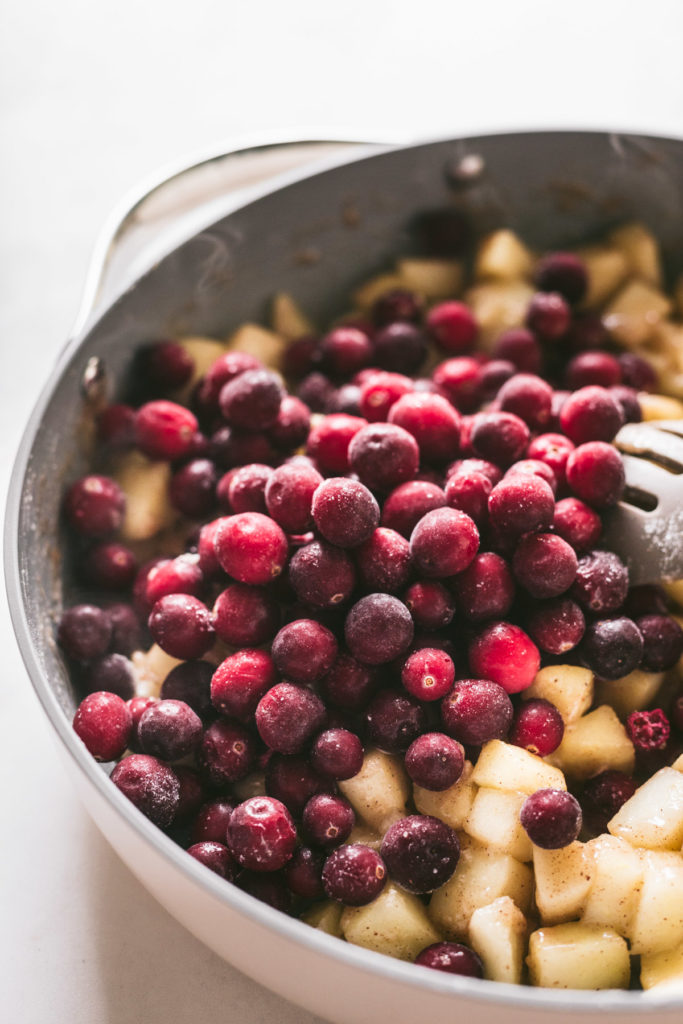 Sautéed Apples in a pan with frozen cranberries on top