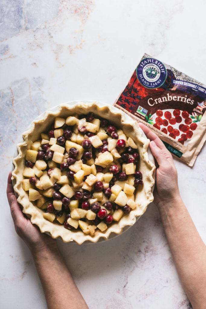 Naket pie being held with hands and a bag of stahlbush next to it