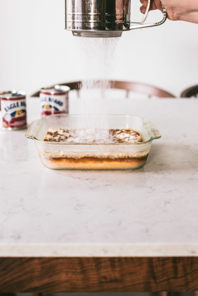 cooked Maple Coconut Gooey Bars being dusted with powdered sugar