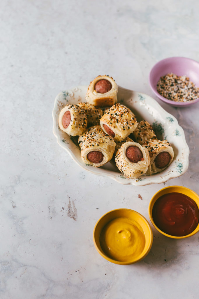 Everything bagel polish dog bites finished and piled in a bowl with condiments on the side