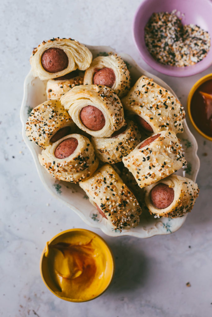 Everything bagel polish dog bites finished and piled in a bowl with condiments on the side