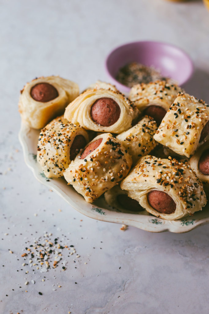 Everything bagel polish dog bites finished and piled in a bowl with condiments on the side