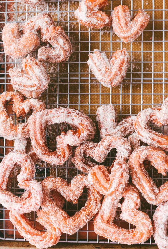 Over head shot of Pink Heart-Shaped Churros cooling on a wire rack.
