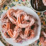 Over head shot of a bowl of Pink Heart-Shaped Churros next to a bowl of ganache.
