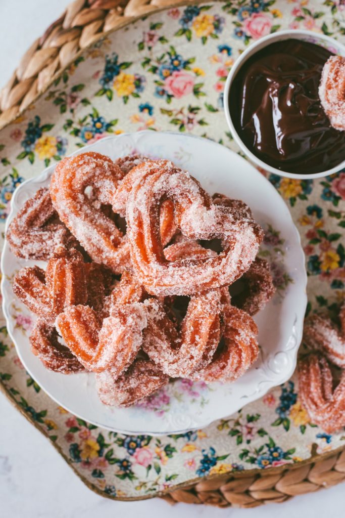 Over head shot of a bowl of Pink Heart-Shaped Churros next to a bowl of ganache.