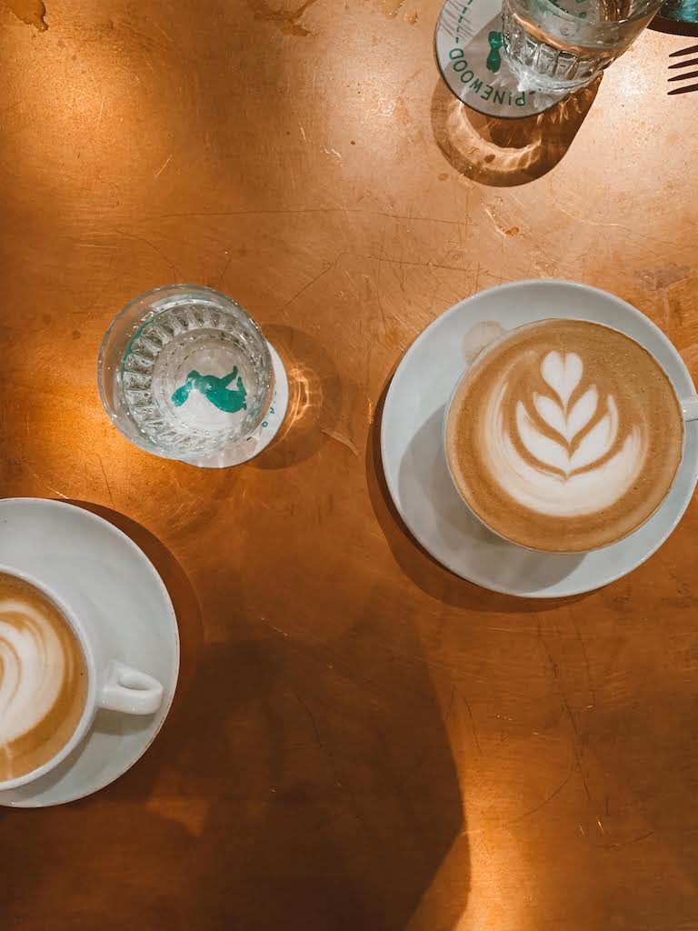Two foamy cappuccinos on a copper table