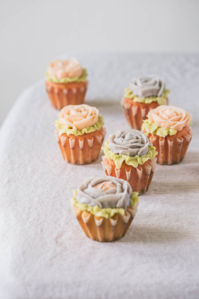 cupcakes on a table decorated with frosting as pink and purple roses