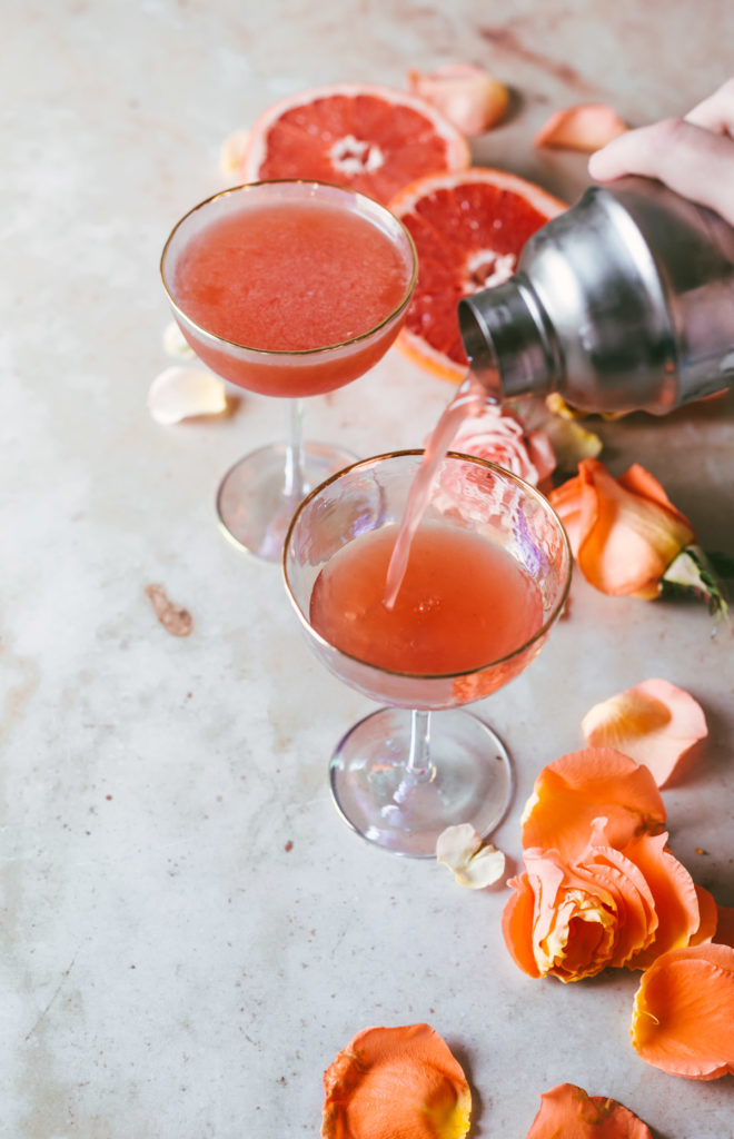 Ruby Bourbon Brown Derby being poured into coups with rose petals on the table