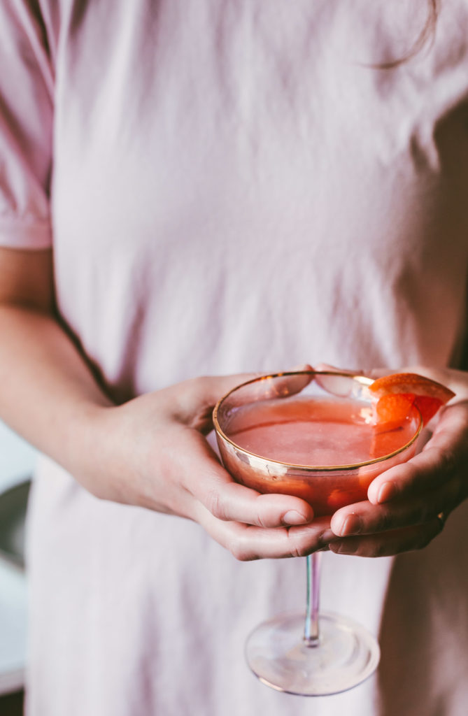 Head on image of woman in pink shirt holding the finished Ruby Bourbon Brown in both hands.