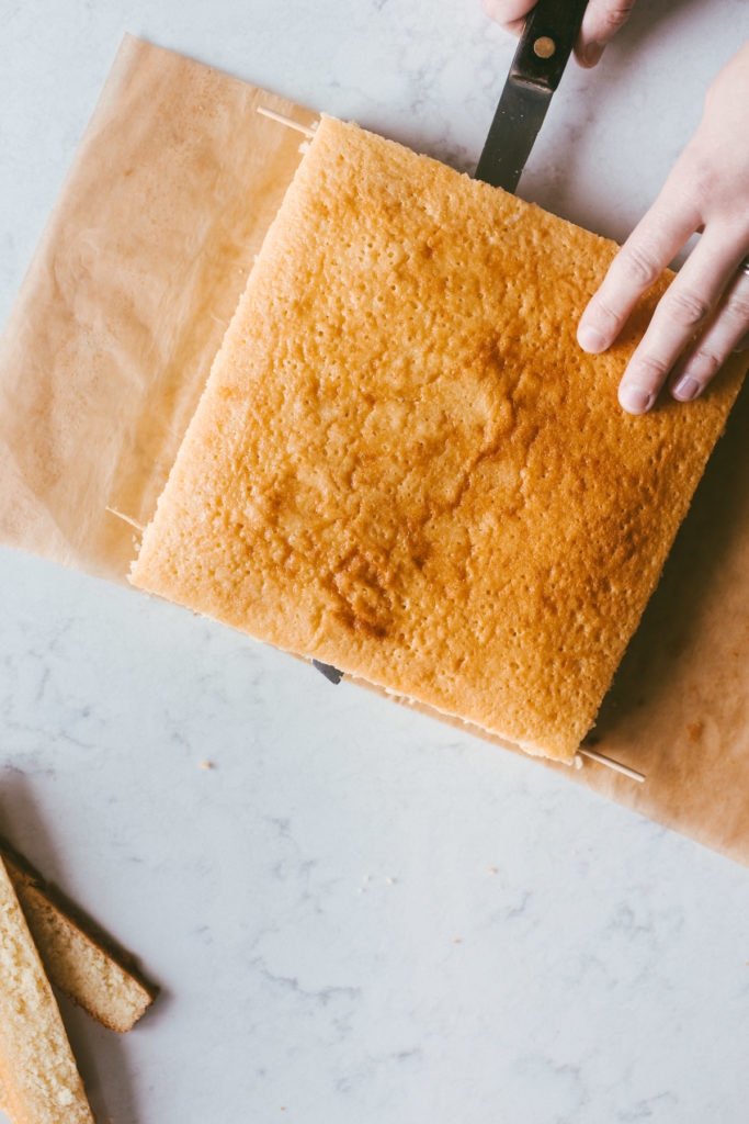 a square yellow cake being sliced into two layers