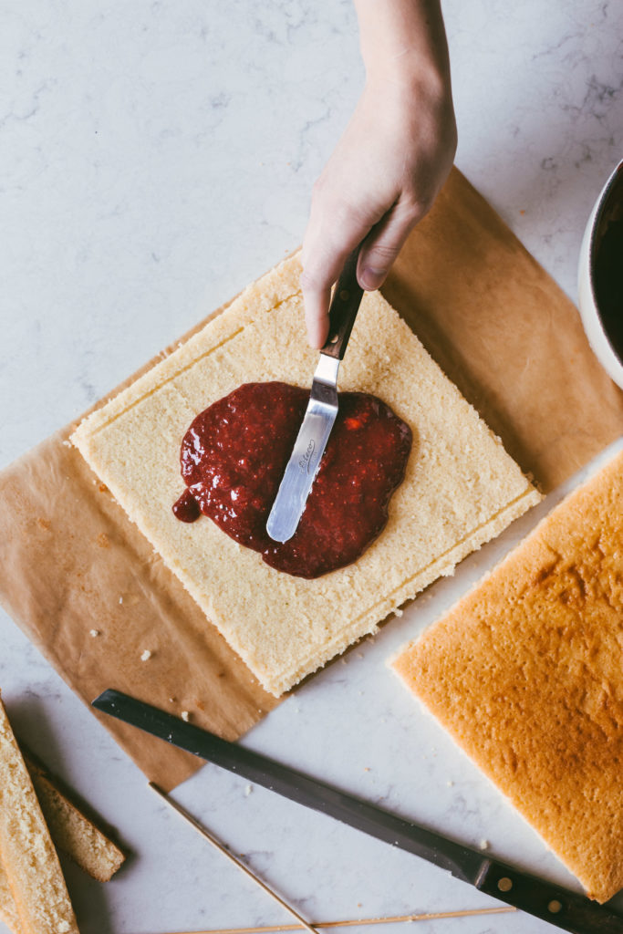 Strawberry filling being spread on one cake layer