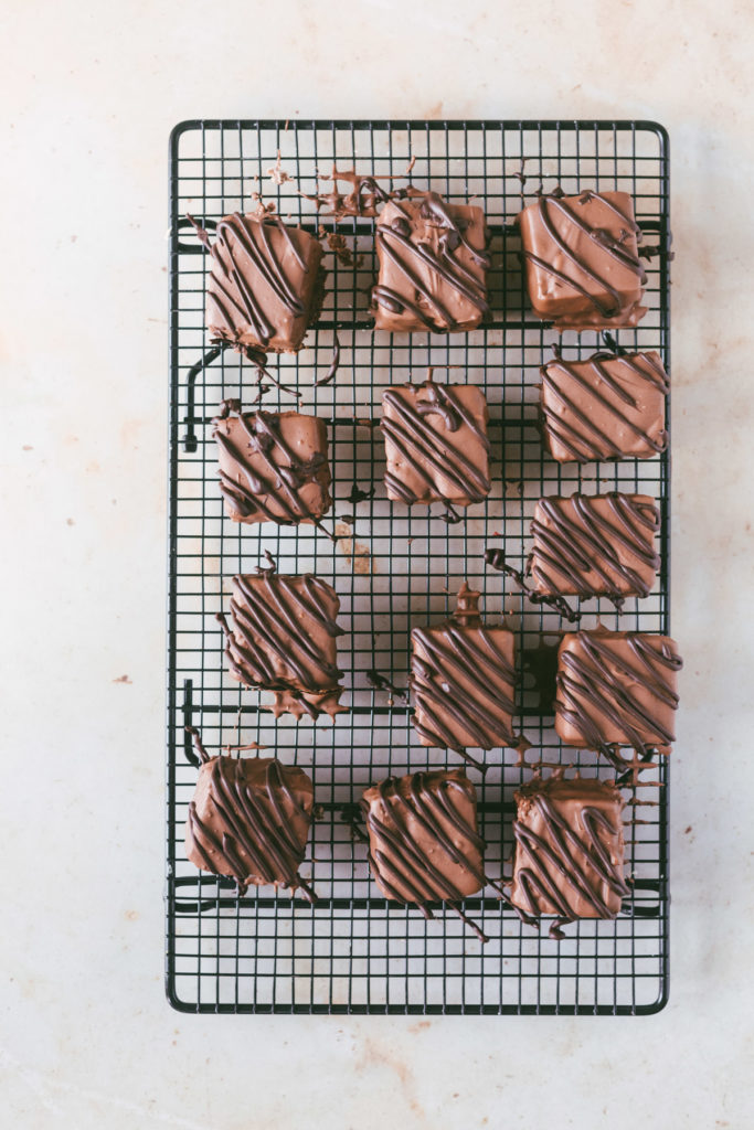 overhead image of the finished petit fours, a milk chocolate coating with a dark chocolate drizzle on a cooling rack.