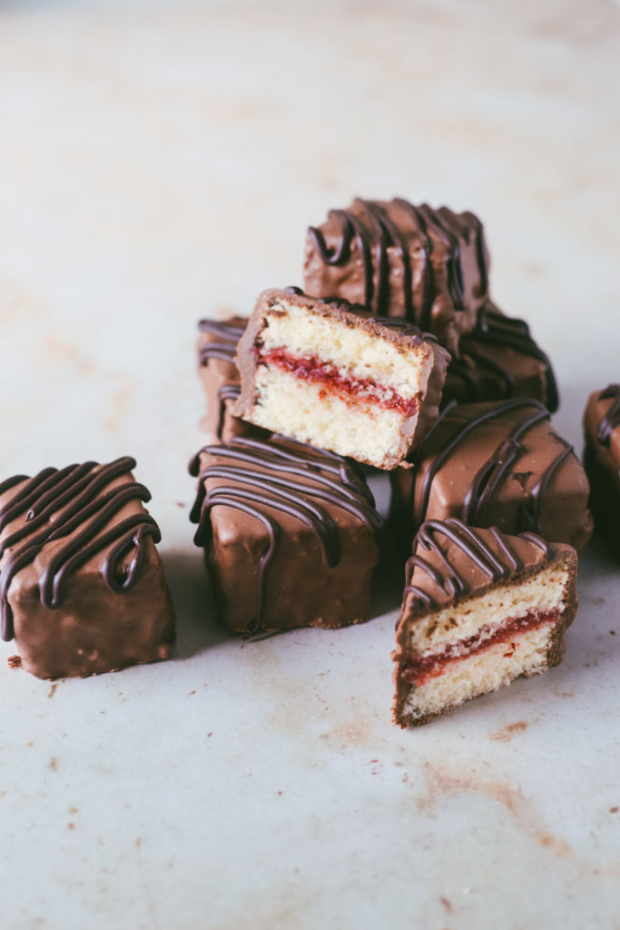 an angled image of the petit fours stacked on eachother with one cut open to reveal the strawberry filling