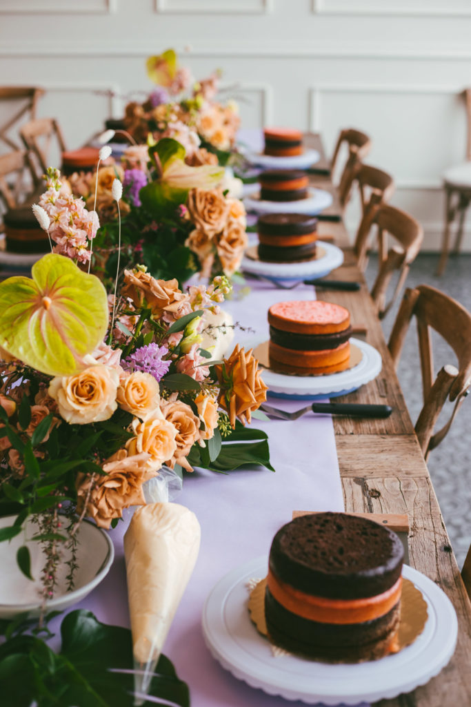 long table with flowers and cake layers ready to be decorated