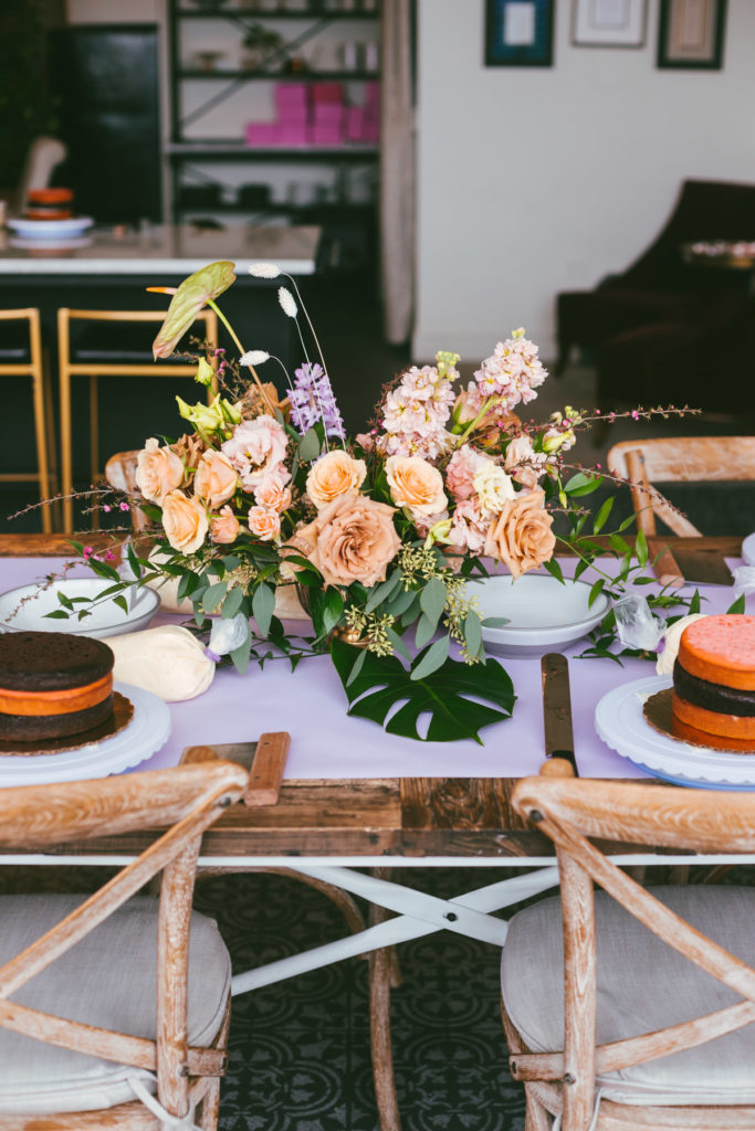 long table with flowers and cake layers ready to be decorated