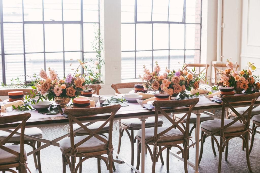 long table with flowers and cake layers ready to be decorated