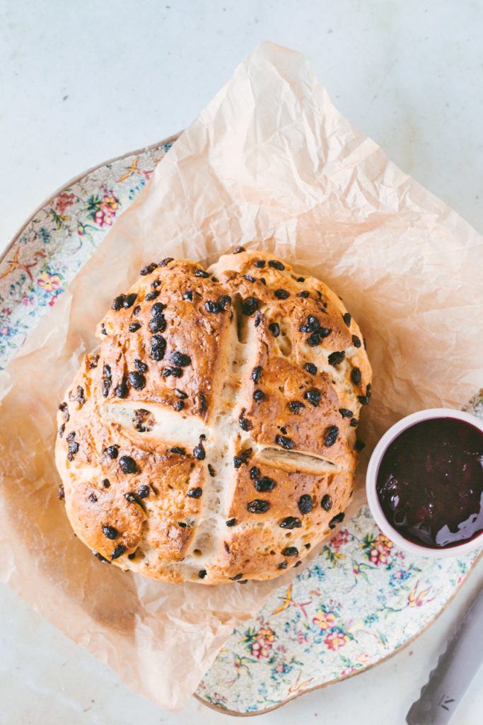 Overhead image of Irish soda bread laying on a floral try under parchment paper with jam on the side