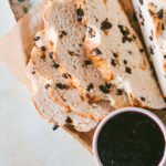 Overhead image of half sliced Irish soda bread laying on a floral try under parchment paper with jam on the side