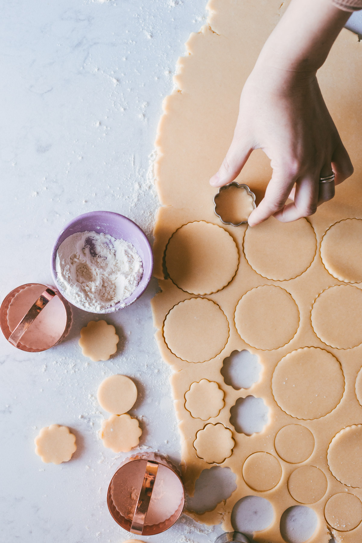 Sugar cookie dough being stamped out by different sized circle cut outs