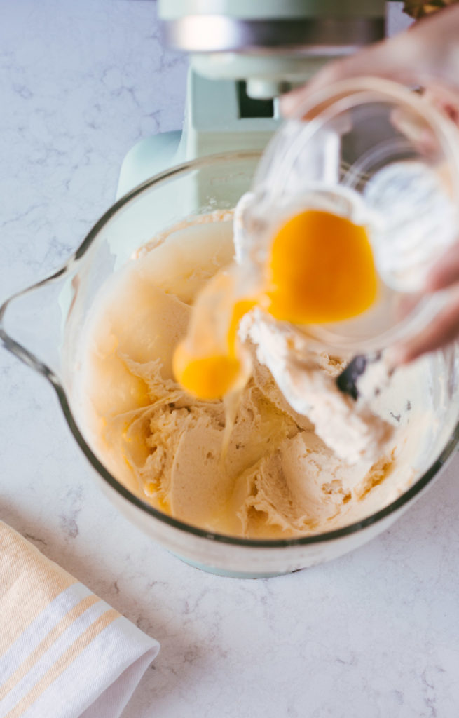 eggs being added to the fluffy sugar and butter mixture