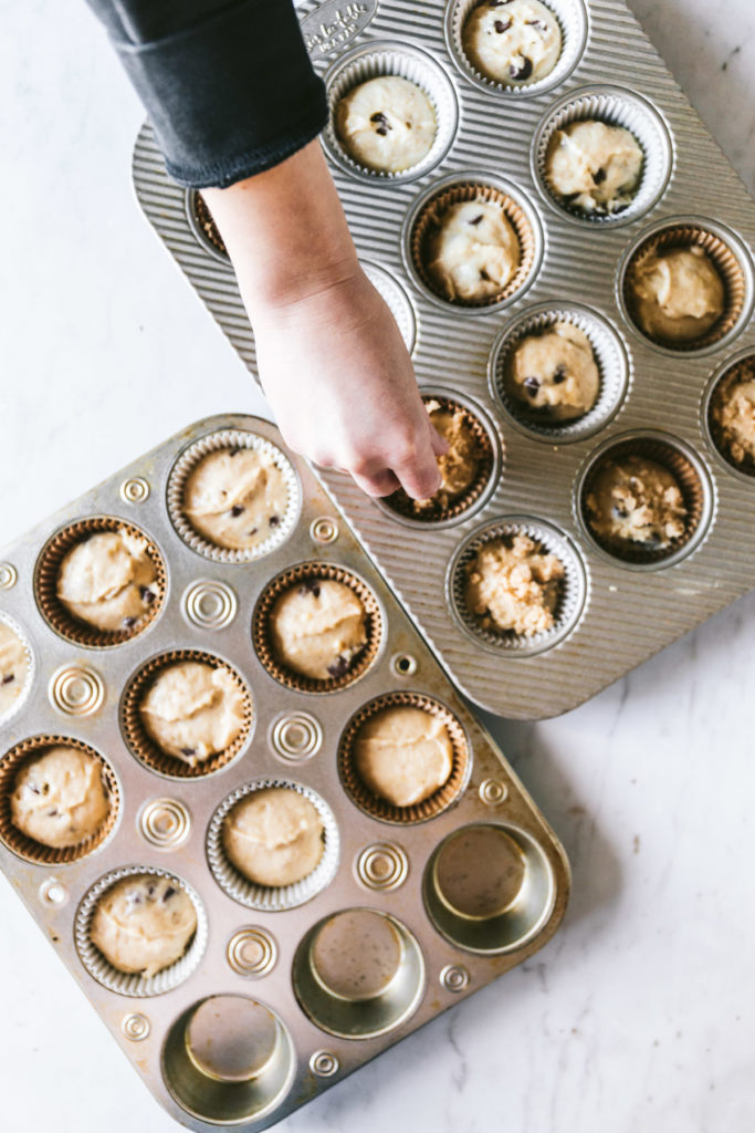 overhead image of muffin two muffin tins and streusel being sprinkled on top