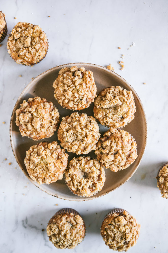 Overhead image of browned butter banana chocolate chip muffins in a bowl with a few scattered around it