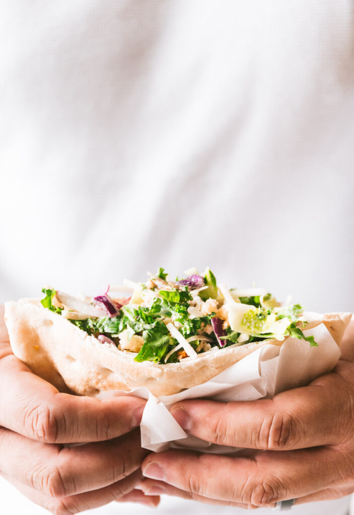 Hands holding a Three Dill Chicken Salad Pitas