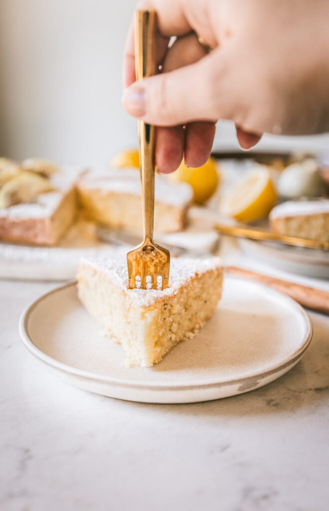 A slice of Head on angle of cake with a slice slightly moved away from the cake with a fork about to take a bight out of it.