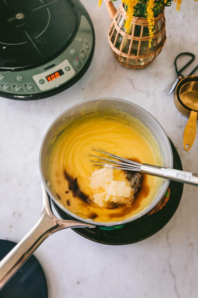 Overhead shot of a saucepan filled with cooked custard and doused with butter and vanilla