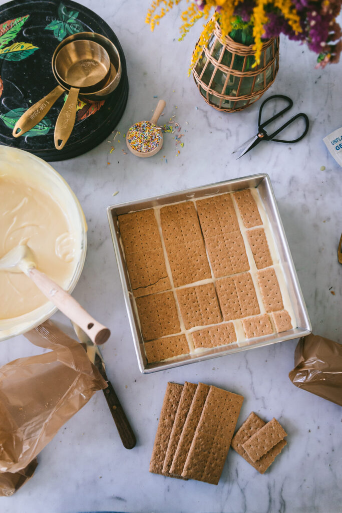a process shot of the layers of graham cracker and custard being filled