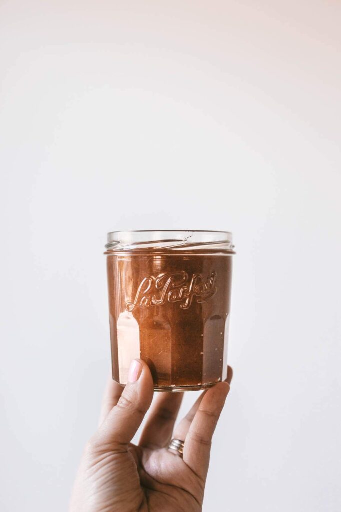 a hand holding a jar of peach butter