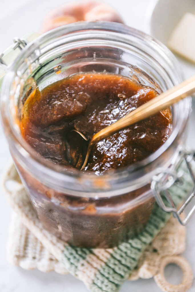 Close look at the peach butter in the jar with a spoon in it