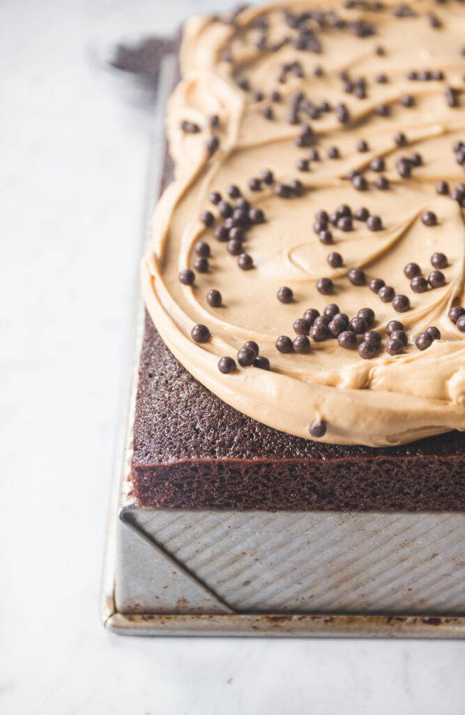 A chocolate sheet cake with peanut butter frosting topped with chocolate crunch balls