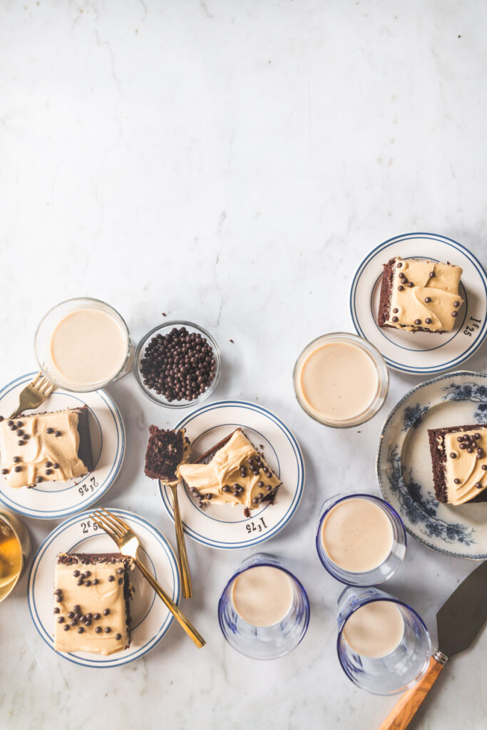 A square slice of A chocolate sheet cake with peanut butter frosting topped with chocolate crunch balls on a small white plate with blue stripes