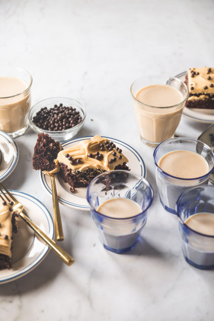 A square slice of A chocolate sheet cake with peanut butter frosting topped with chocolate crunch balls on a small white plate with blue stripes